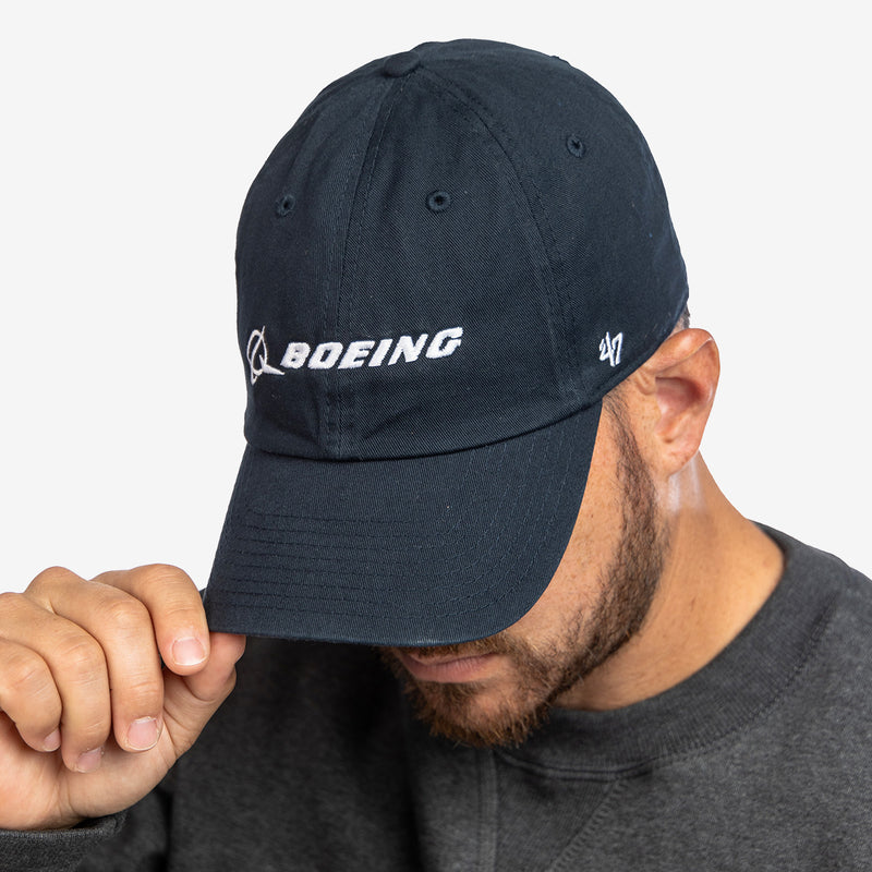 Man wearing a navy blue cap with 'Boeing' logo on a light gray background