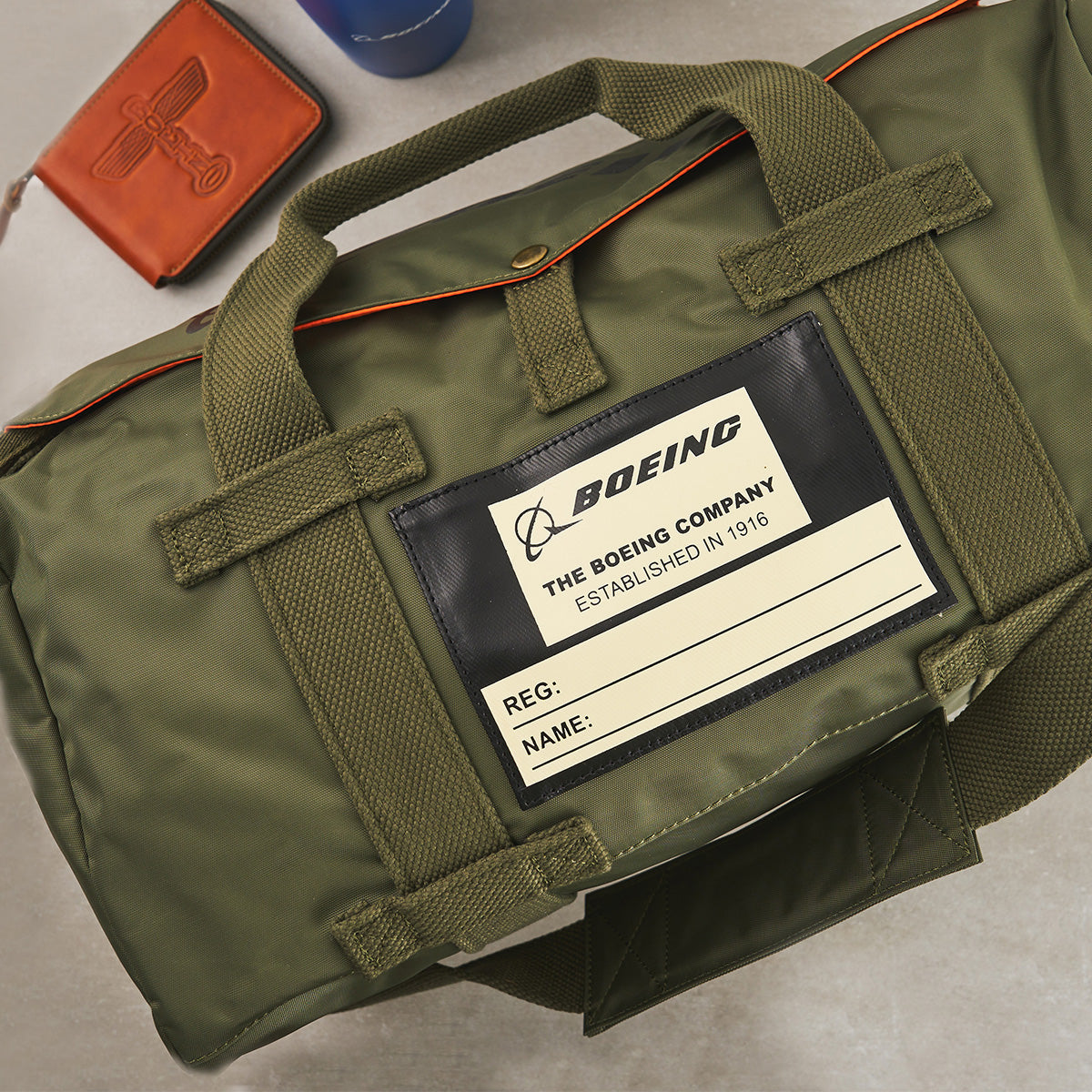 Green duffel bag with a Boeing Heritage label on a gray surface