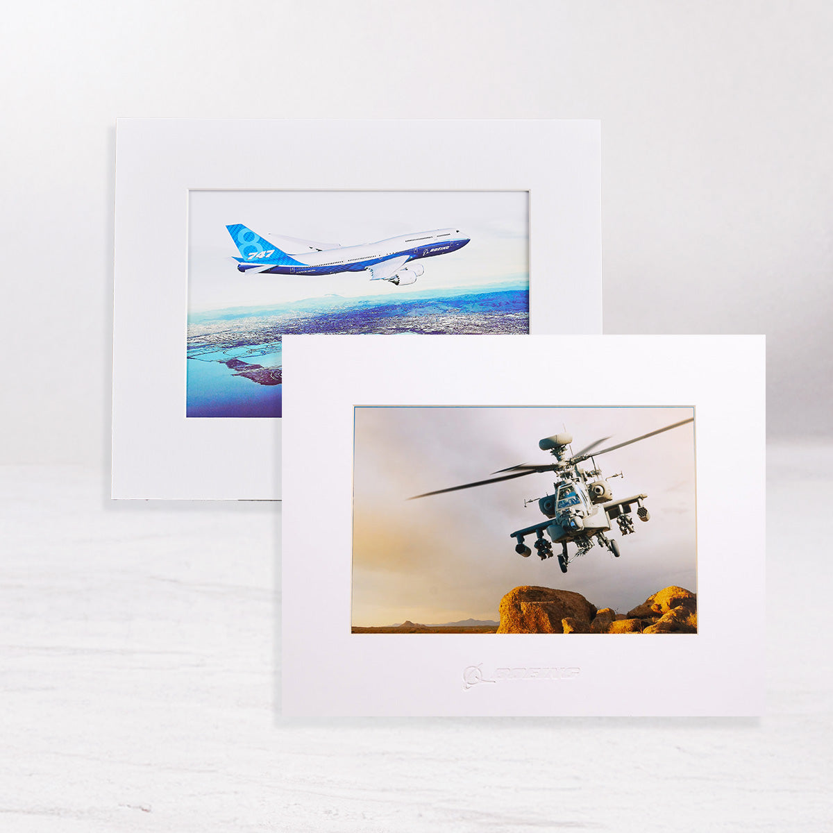 Two framed pictures of Boeing aircraft,  an airplane and a helicopter on a white surface.