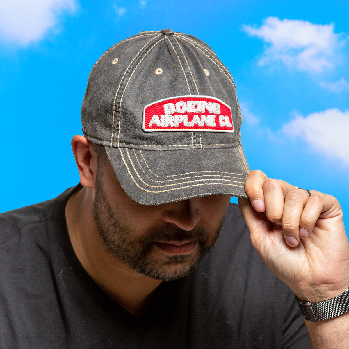 A person wearing a cap with the text "Boeing Airplane Co." on it, set against a blue sky background.