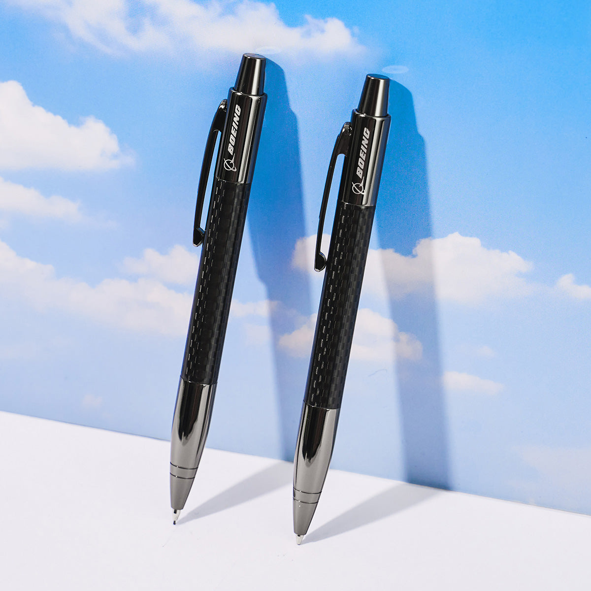 Two black pens featuring the Boeing logo, set against a blue sky backdrop.