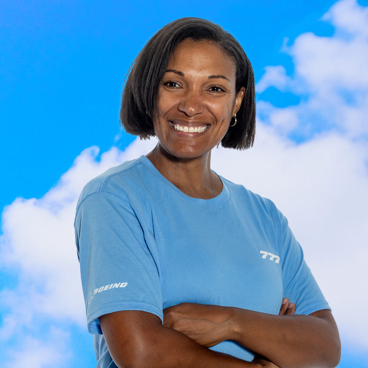 A person wearing a light blue Boeing 777 t-shirt from the Series Collection, posed against a blue sky background.