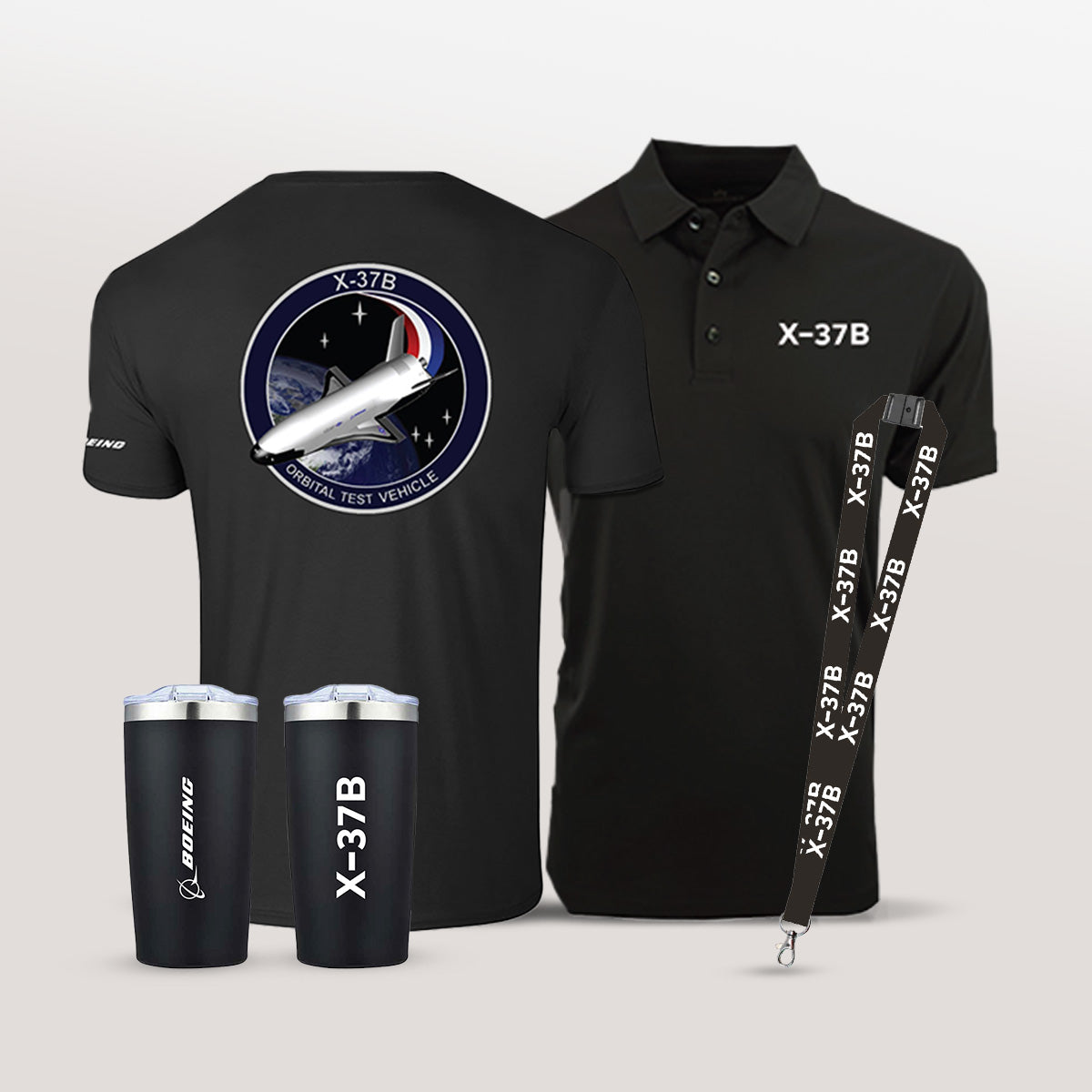 Black t-shirt, polo shirt, tumblers, and lanyard with X-37B logo and graphic on a light gray background