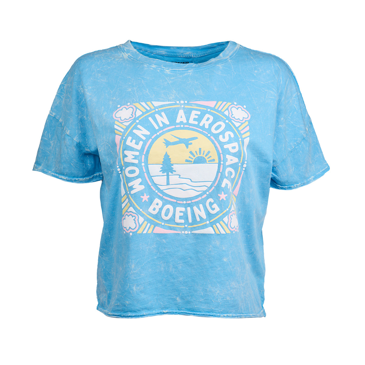 The Boeing Women In Aerospace Commercial Womens T-Shirt features a light blue, super-soft short-sleeve design with vintage-inspired pastel graphics of mountains, trees, sun, clouds, and an airplane on the front. Brand: Boeing.