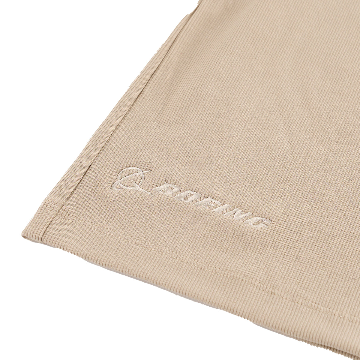 Close-up of a beige, ribbed Greyson Boeing Womens Orion Tank Top with neat stitching and FORME embroidered in white, highlighting BOEINGs ultra-soft, shape-retention fabric.