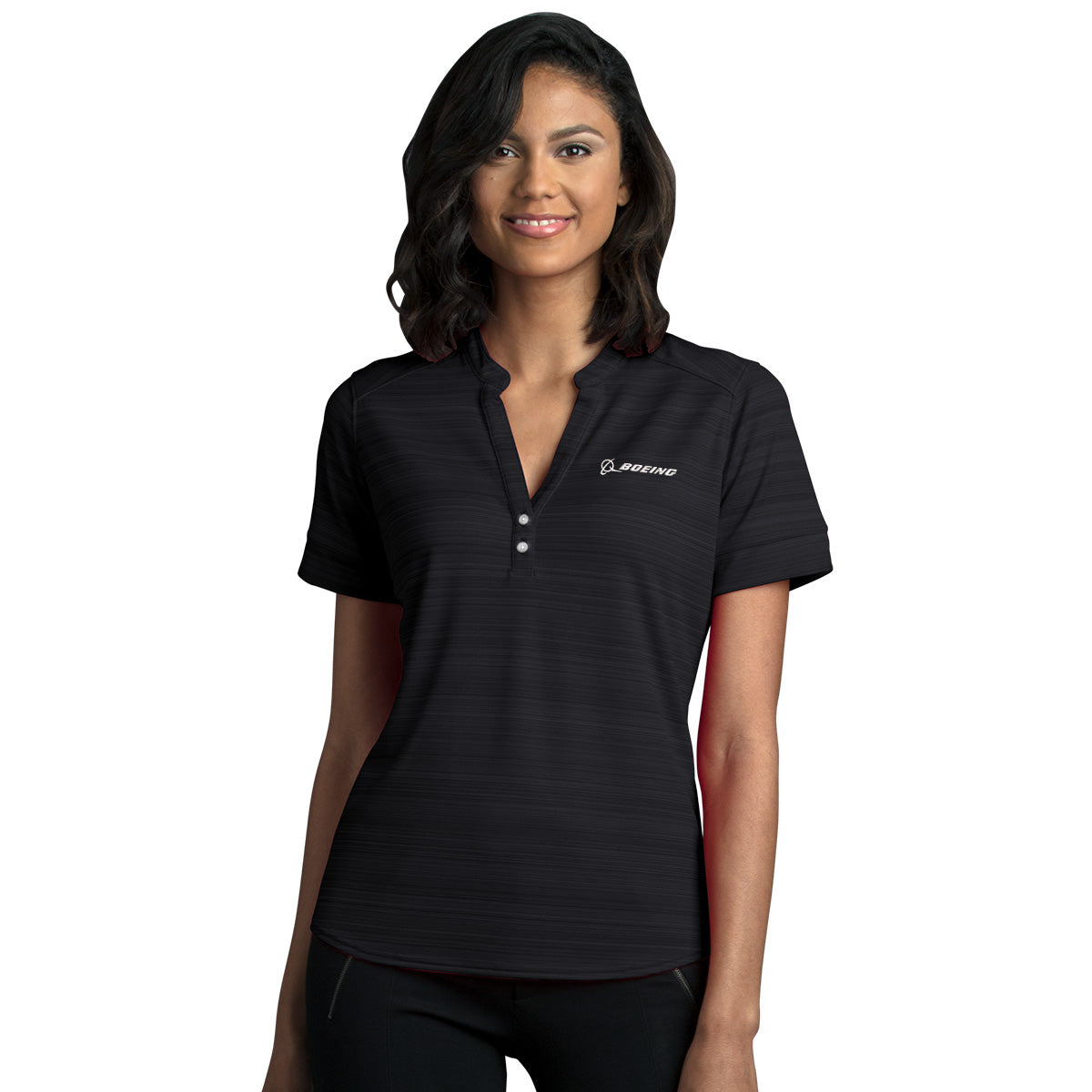 A woman with shoulder-length dark hair smiles in a black Boeing Women's Strata Polo, featuring moisture-wicking fabric and a BOEING embroidered logo on the left chest, standing against a plain white background.