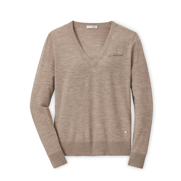 The Peter Millar Boeing Women’s Excursionist Flex V-Neck Sweater by BOEING is a light brown merino wool piece with long sleeves and subtle stitching, featuring an embroidered logo on the left chest. Shown laid flat on a white background.