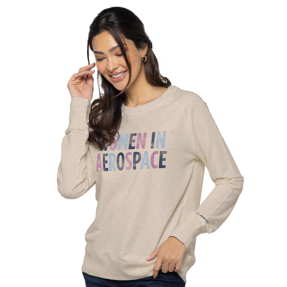 A person with long hair smiles wearing the Boeing Women In Aerospace Womens Crewneck Sweatshirt, showcasing WOMEN IN AEROSPACE in bold text. Speckled details add charm as they pose against a plain white background, symbolizing equality in the aerospace industry.