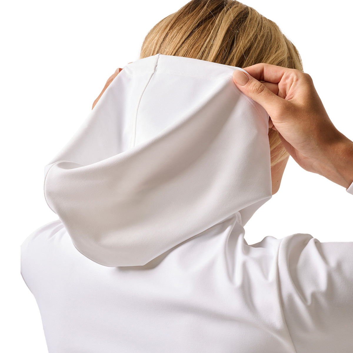 A woman covers her face with the johnnie-O Boeing Women’s Nalla Performance Hoodie by BOEING, made from moisture-wicking fabric.