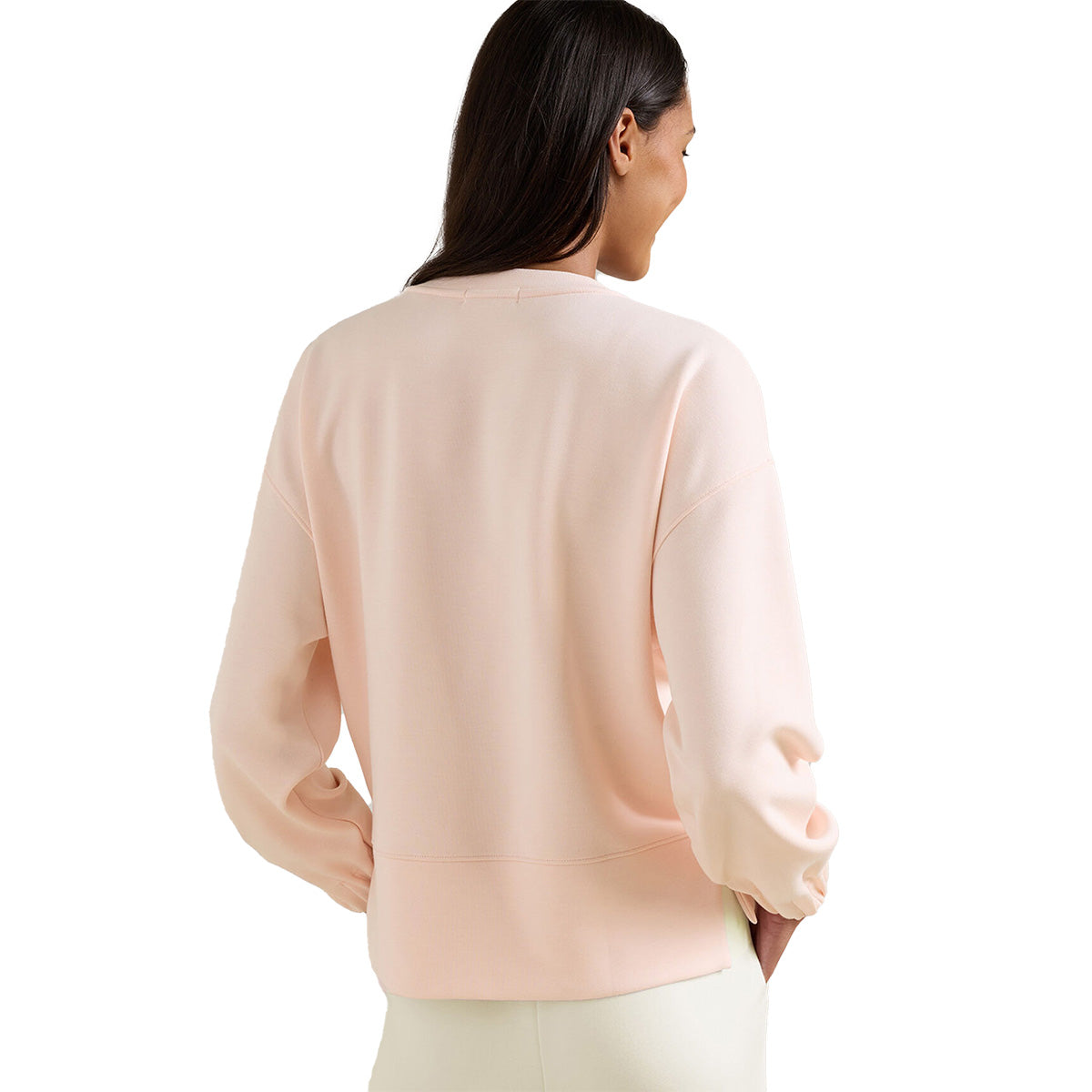 A woman with long dark hair is shown from the back wearing a light pink Peter Millar Boeing Women’s Flora Knit Mélange Crewneck and light-colored pants, standing against a white background.