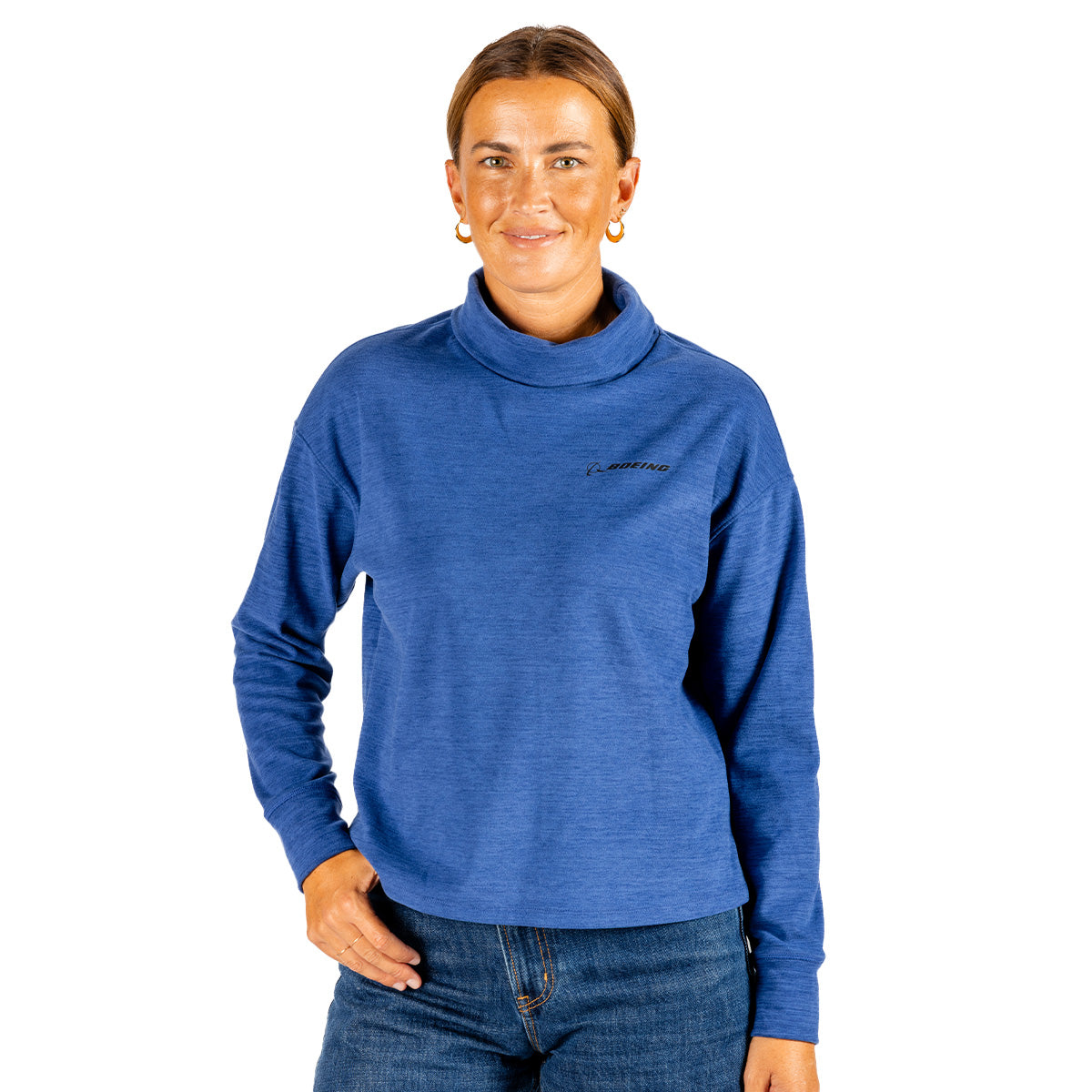 A woman wears a long-sleeved, blue, mock neck Boeing Women’s Cashmere Fleece Mock Neck Pullover with a small Boeing logo on the left chest.