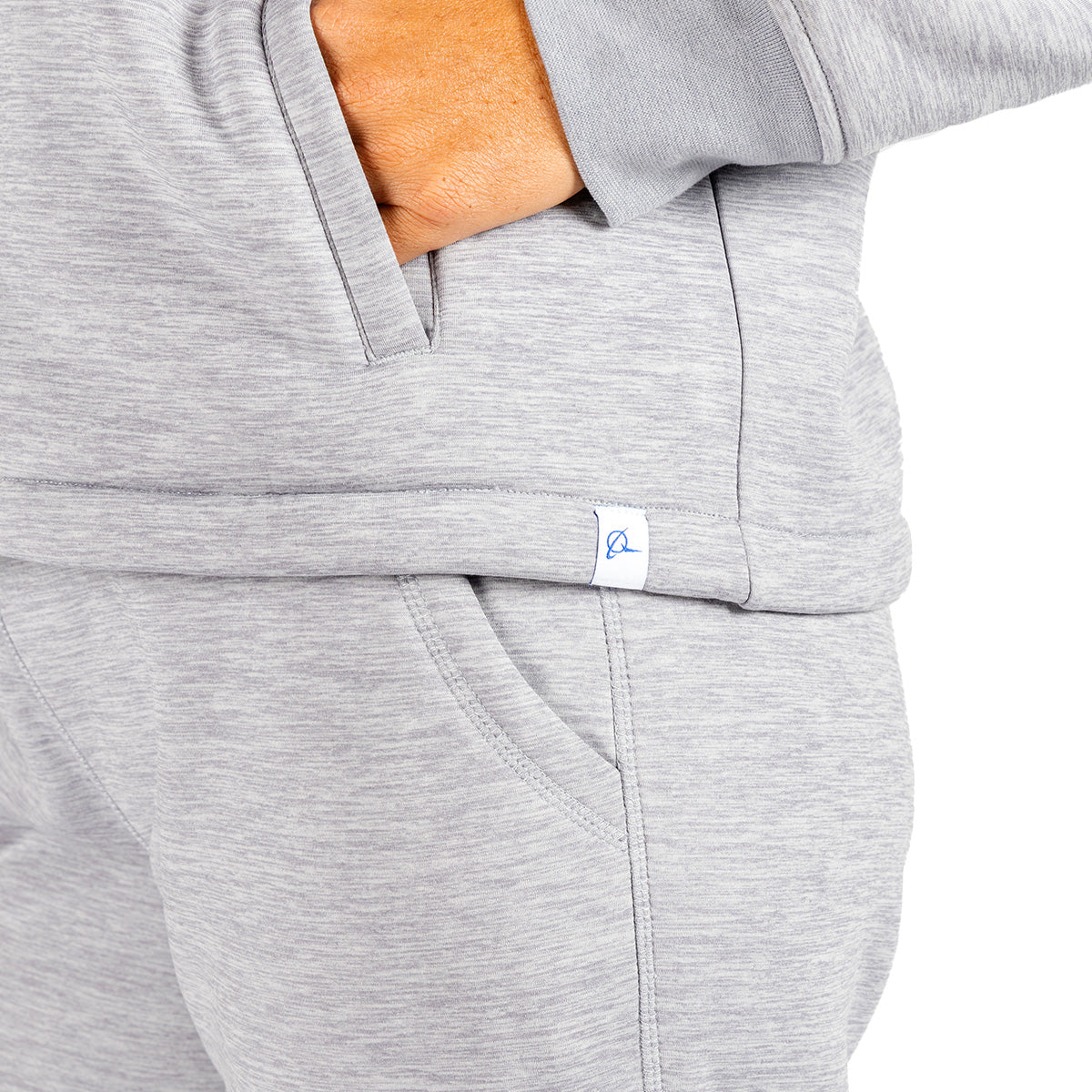 Close-up of a person wearing a light gray heathered Boeing Women’s Luxe Plush Full-Zip Hoodie and matching pants, with a hand tucked into the pocket.