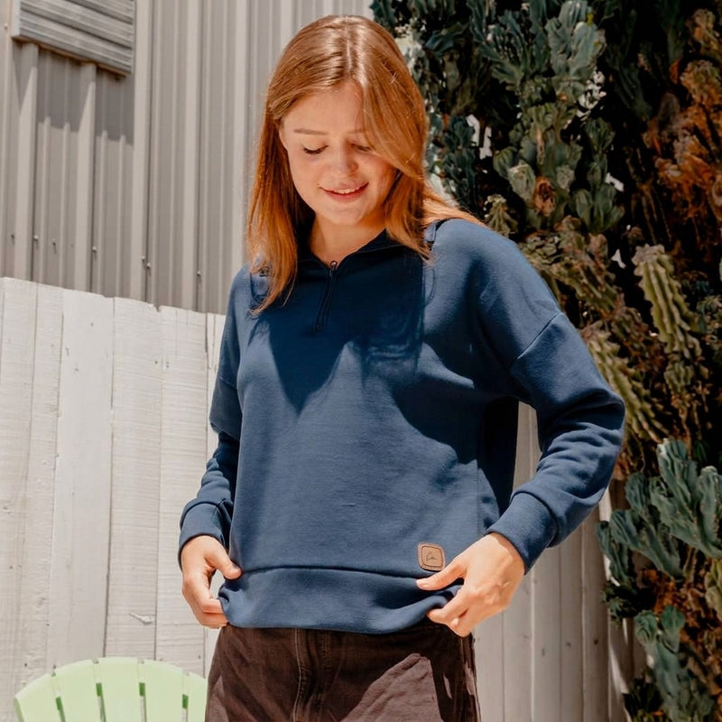 Woman wearing a navy blue quarter zip with a Boeing Symbol patch on the bottom right. 