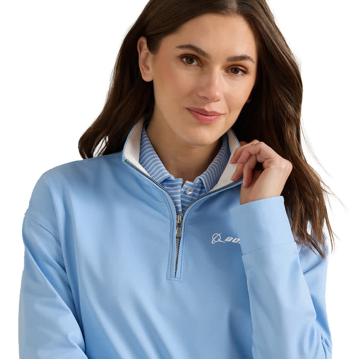 A woman with long brown hair, touching her collar and looking at the camera against a plain white background, wears a light blue Peter Millar Boeing Women’s Coolspun Lite Quarter-Zip by BOEING over a blue and white striped shirt.
