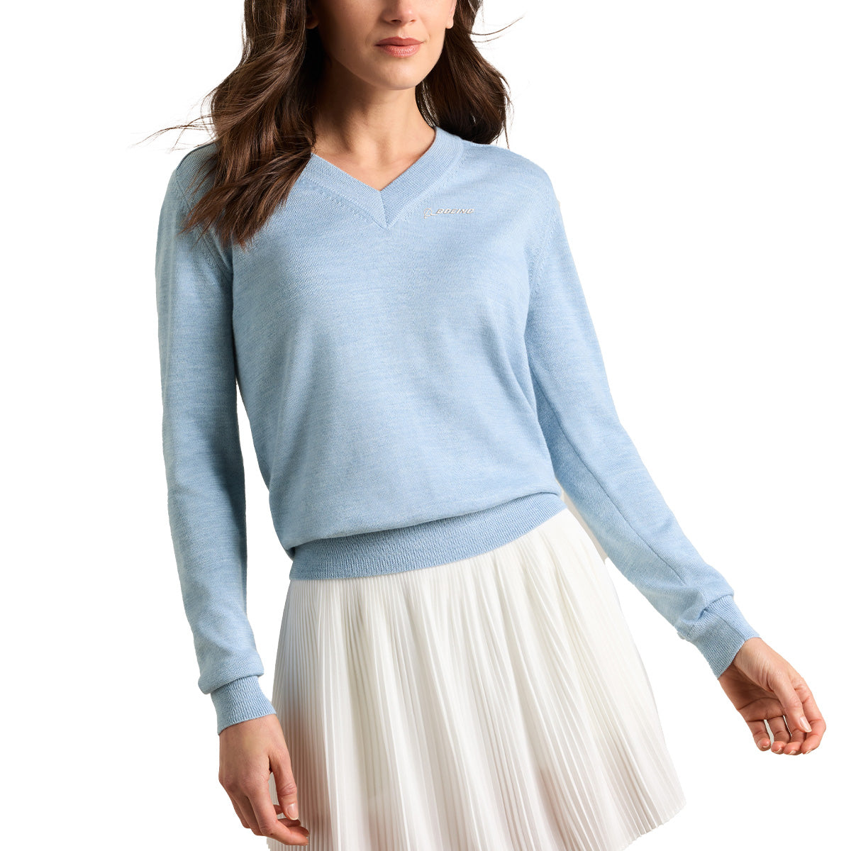 A woman wearing the Peter Millar Boeing Women’s Solarspun Sport V-Neck Sweater in light blue and a white pleated skirt stands against a white background, with her head partially out of frame. The sweater is by BOEING.
