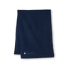The Peter Millar Boeing Cashmere Wrap by Boeing is a dark blue cashmere scarf featuring a small silver circular emblem and the Boeing logo near one edge, stylishly displayed on a plain white background.