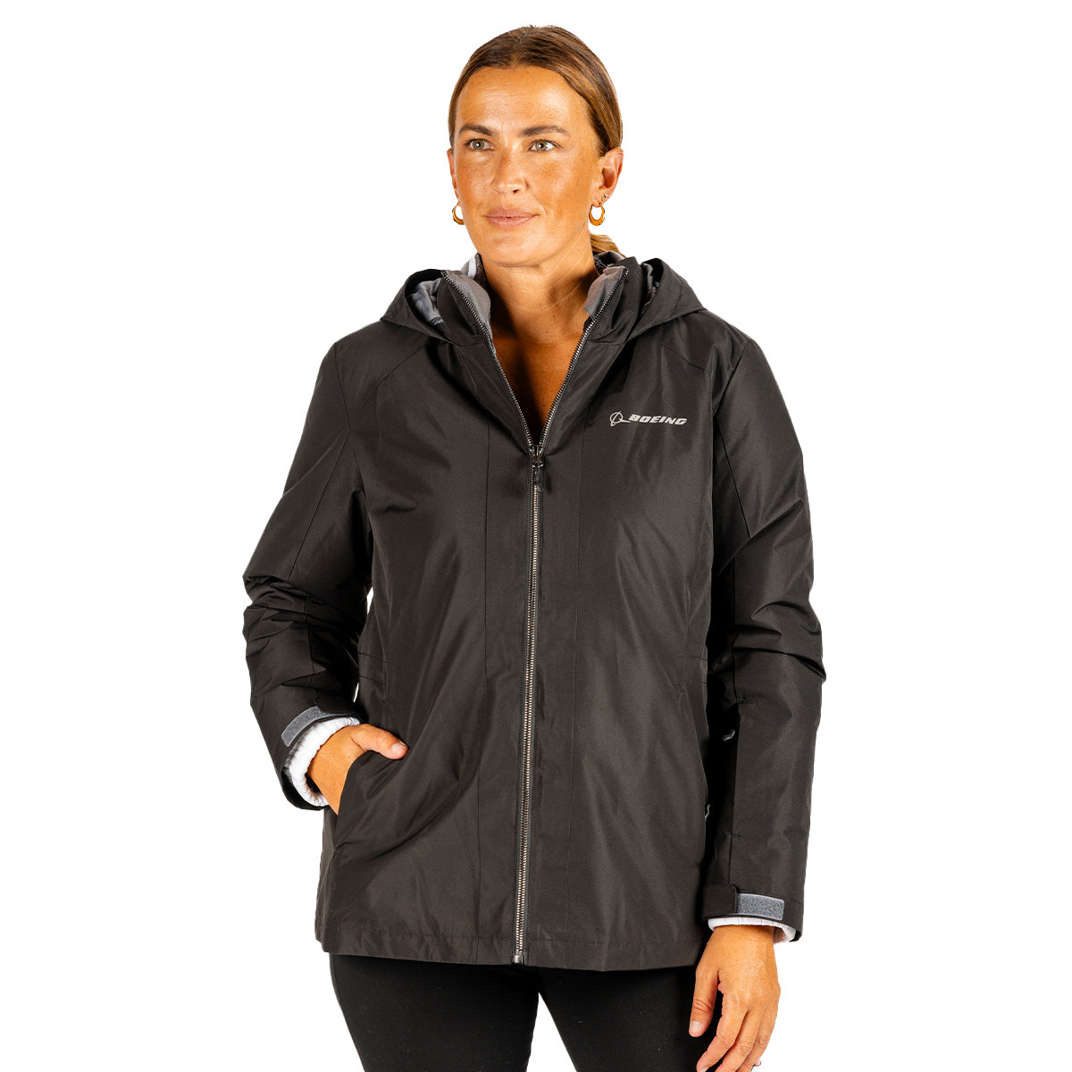 Woman wearing a black Boeing Women’s 3-in-1 Systems Jacket, a water-resistant hooded style with a front zipper and a white logo on the chest.