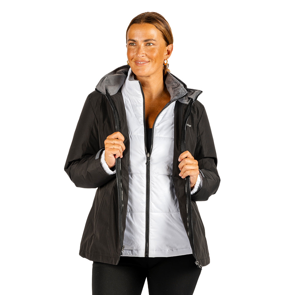 A woman wears a Boeing Women’s 3-in-1 Systems Jacket, featuring a black hooded shell layered over a white quilted vest.