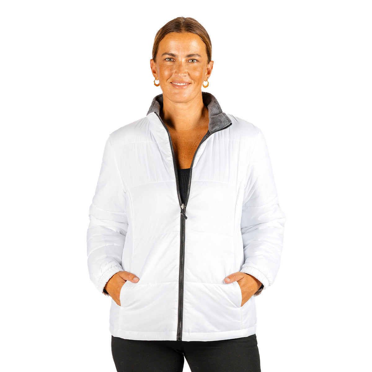 Woman wearing a white, water-resistant, quilted Boeing Women’s 3-in-1 Systems Jacket made from recycled fabric, featuring a zip-up front, pockets, and a gray inner lining.