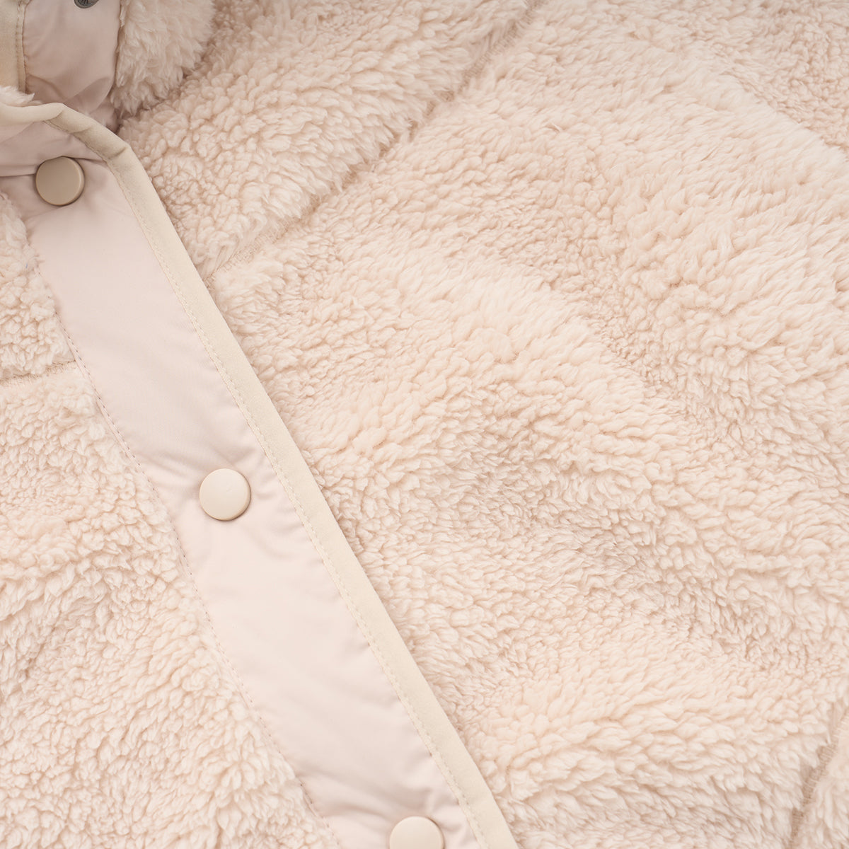 Close-up of the Boeing Women's Sierra Sherpa Long Jacket by BOEING, featuring soft beige fleece, snap-button closure, and smooth trim along the button line.