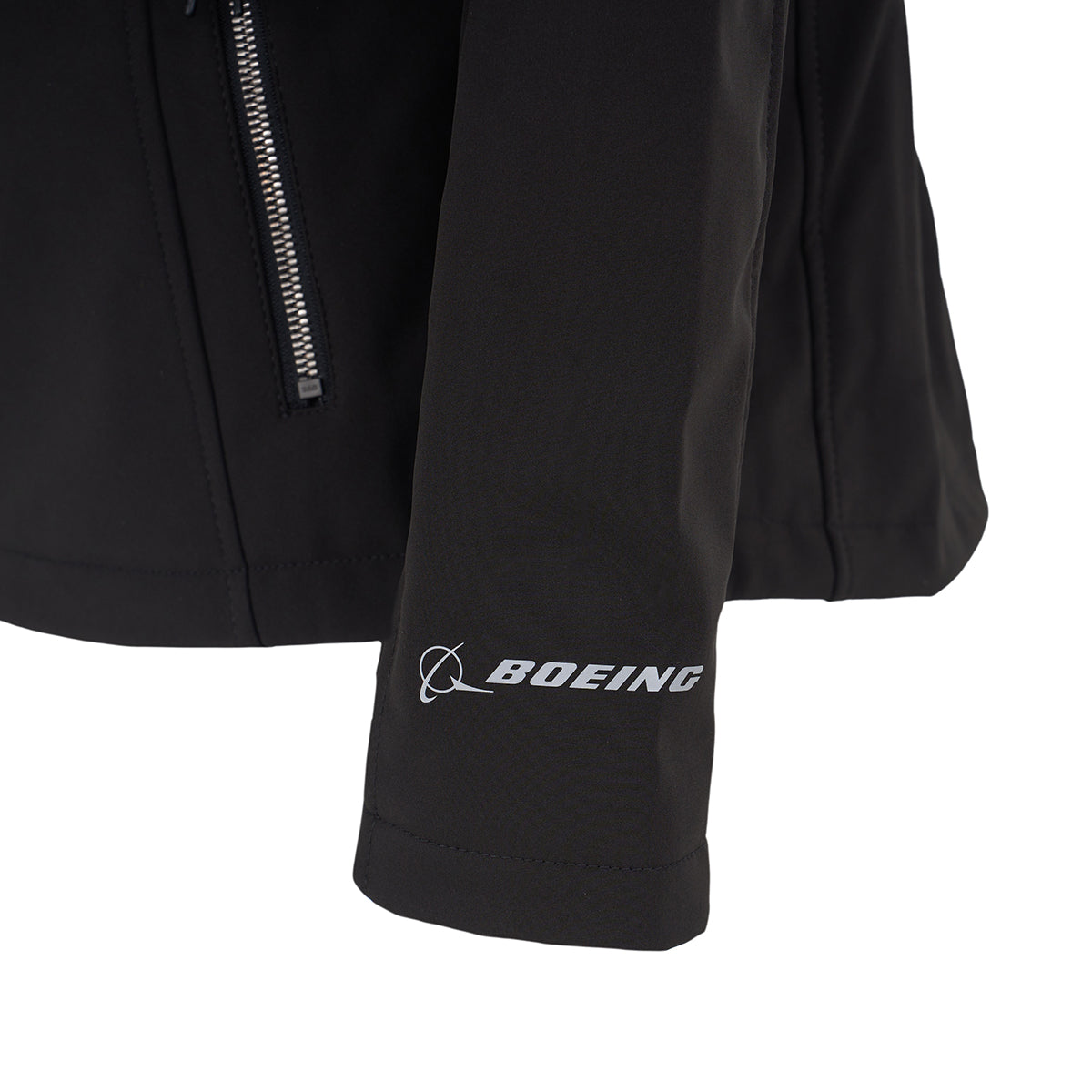 A close-up of the Boeing Women's Aeris Super-Softshell Jacket sleeve shows the white BOEING logo printed near the cuff and a zippered pocket, all on a black, recycled polyester super-softshell jacket.
