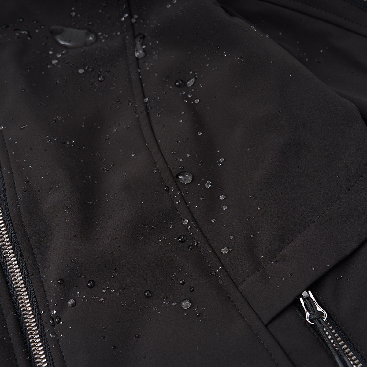 Close-up of the Boeing Women's Aeris Super-Softshell Jacket by BOEING, made from recycled polyester. The black jacket showcases water resistance with droplets on its surface, plus visible zippers and seams.