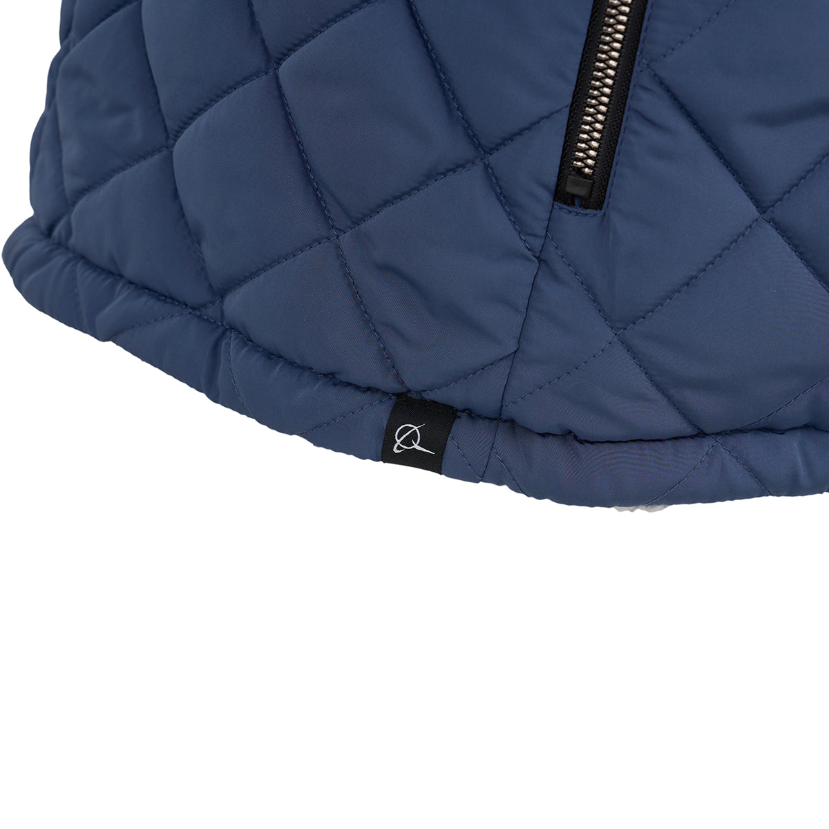 Close-up of the blue quilted, wind-resistant fabric with black zipper and logo tag at the hem on the BOEING Women's Stratus Lite Reversible Vest, highlighting signature details.