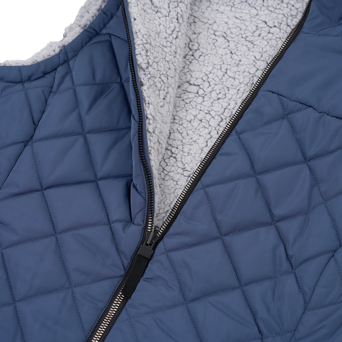 A close-up of the Boeing Women's Stratus Lite Reversible Vest by BOEING in blue, featuring a wind-resistant quilted design with a partially unzipped front that reveals a soft white fleece lining.