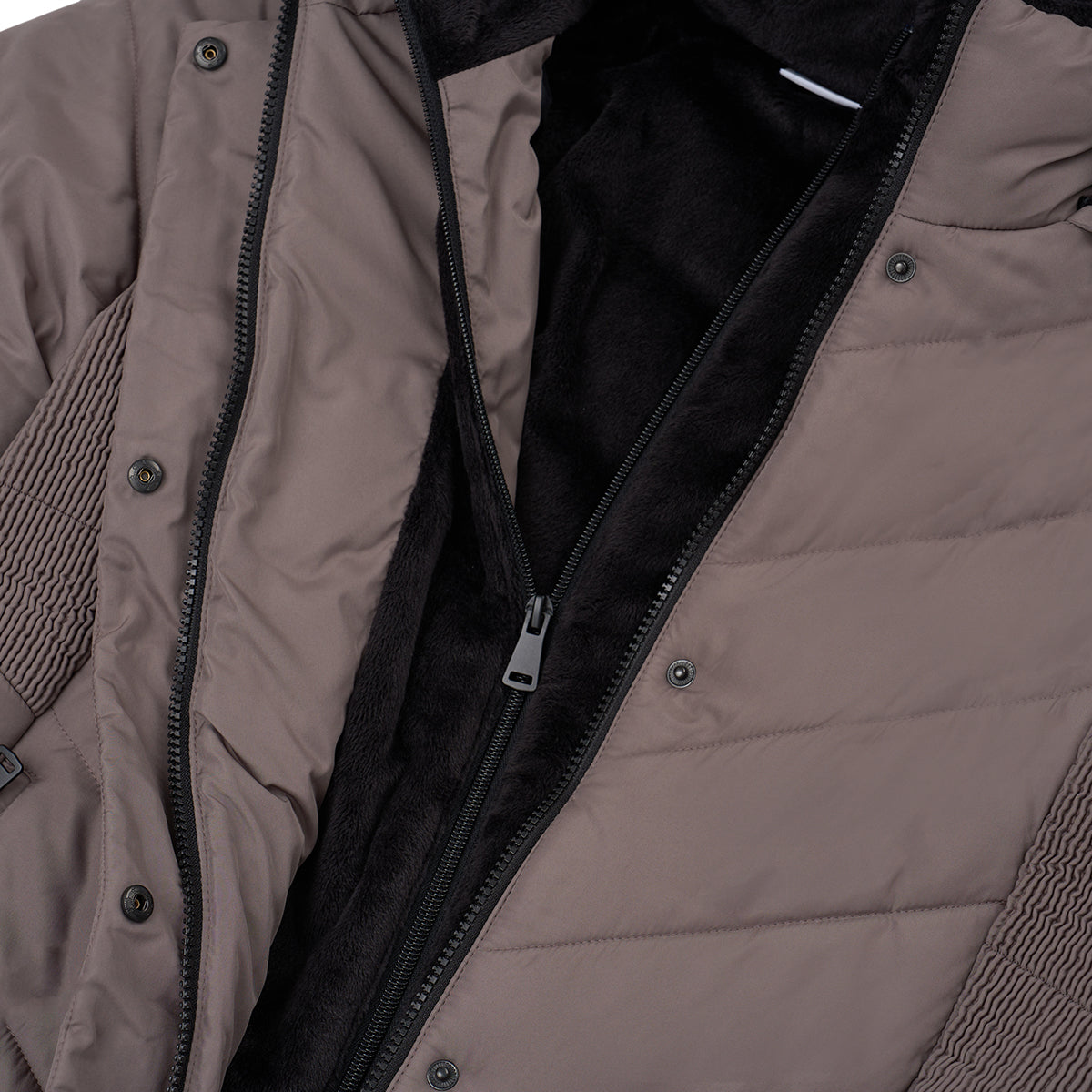 Close-up of the Boeing Women's Quilted Butterpile Jacket by BOEING in taupe, showing its wind-resistant design, black fuzzy lining, zipper and snap closures, plus ribbed side panels. The jacket is partially unzipped to display the interior.