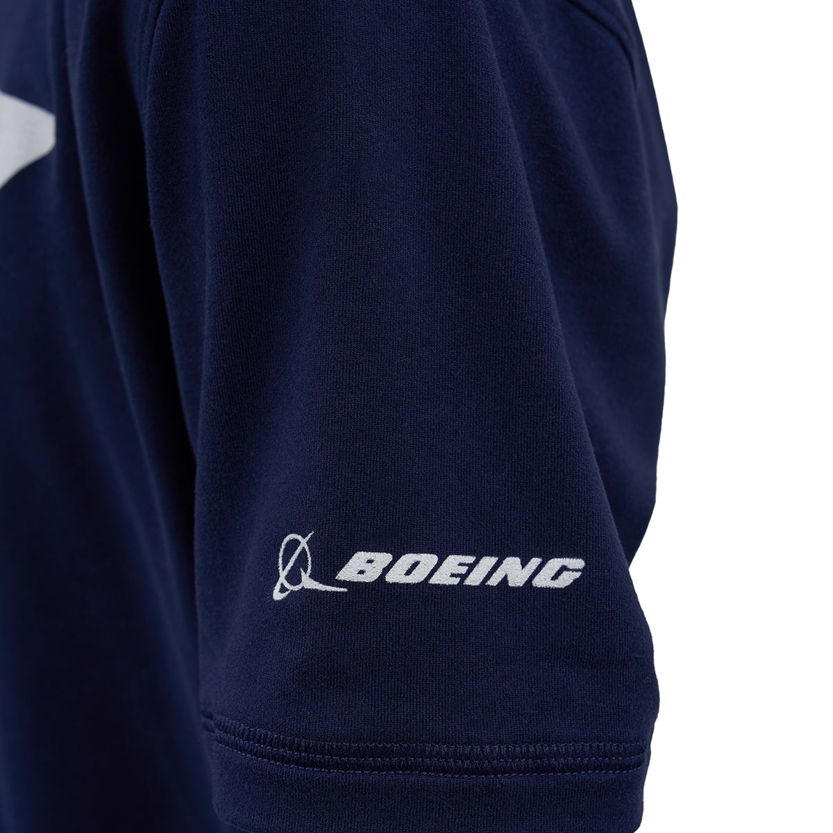 A close-up of the navy sleeve of the Boeing 787 Dreamliner Velocity Kids’ Tech Stretch T-Shirt by BOEING, showing the white Boeing logo near the hem.