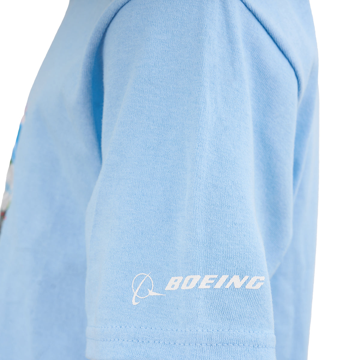 A close-up of the Boeing Rosie Kids T-Shirt by BOEING, featuring light blue cotton jersey fabric, a white BOEING logo, and a stylized airplane graphic on the lower sleeve.