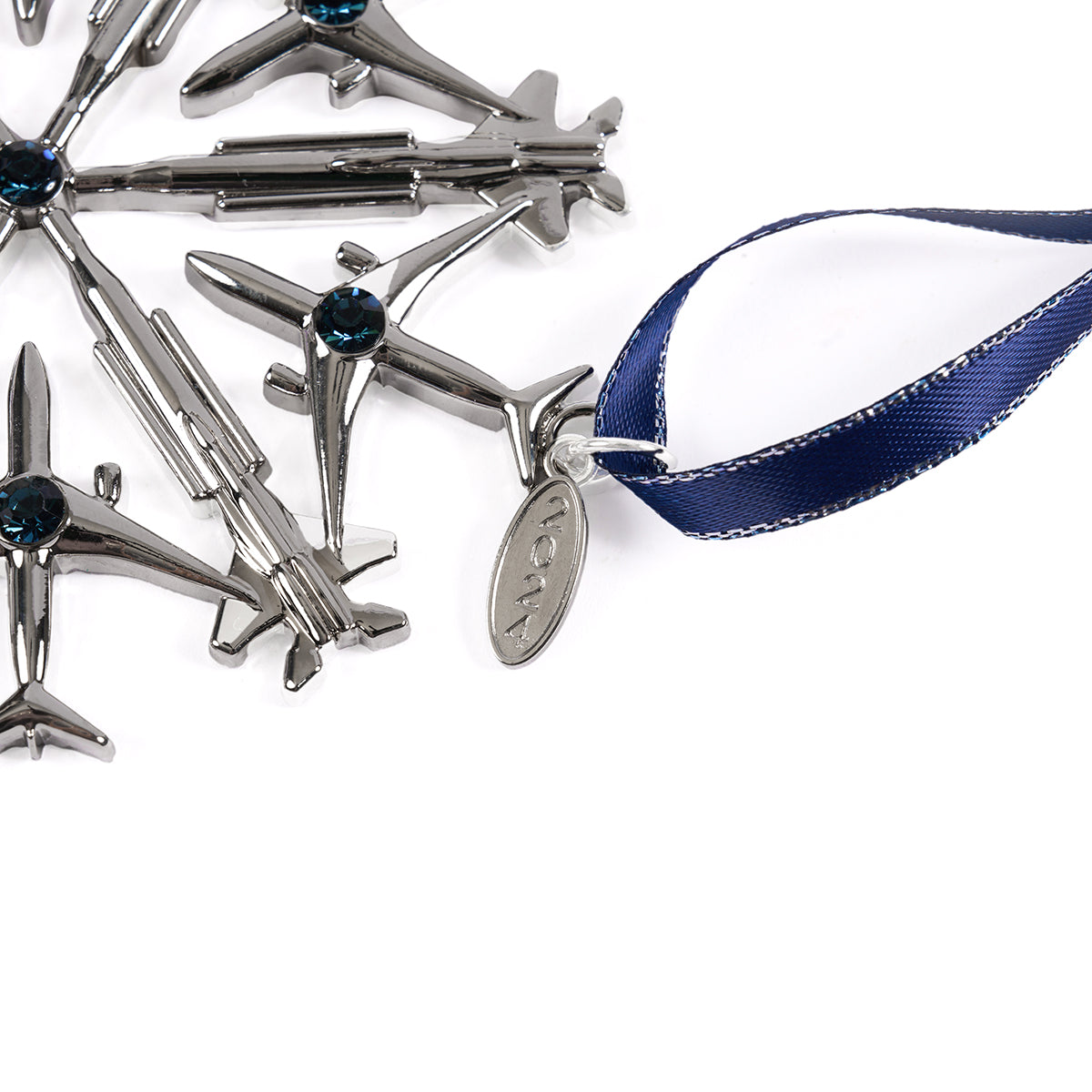 The Boeing 2024 Jet Snowflake Ornament is a silver snowflake crafted from miniature F-15EX Eagles and 787 Dreamliners, adorned with blue gems, a dark blue ribbon, and an inscribed oval tag.