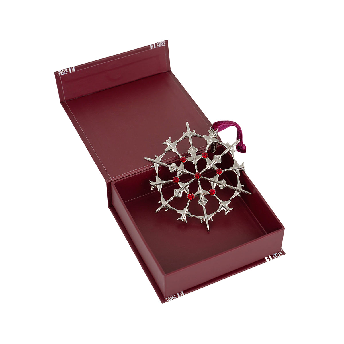 The Boeing 2025 Jet Snowflake Ornament by BOEING, featuring red gems and a red ribbon, comes in an open maroon book-style box—an elegant holiday gift for aviation enthusiasts.
