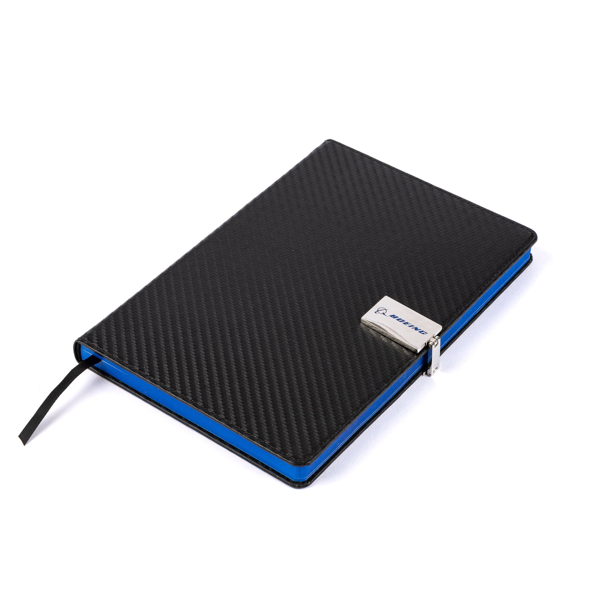 The Boeing Stores PU hardcover Boeing Carbon Fiber Notebook, with a blue edge and silver clasp, sports a small blue logo and black ribbon bookmark. It sits diagonally on a plain white background.