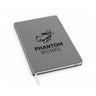 The Boeing Phantom Works Leather Bound Notebook by BOEING is shown closed against a white background. This gray premium notebook features a black logo of a figure in a hat and mask above the text “PHANTOM WORKS,” includes 70GSM paper, and comes with a white ribbon bookmark.