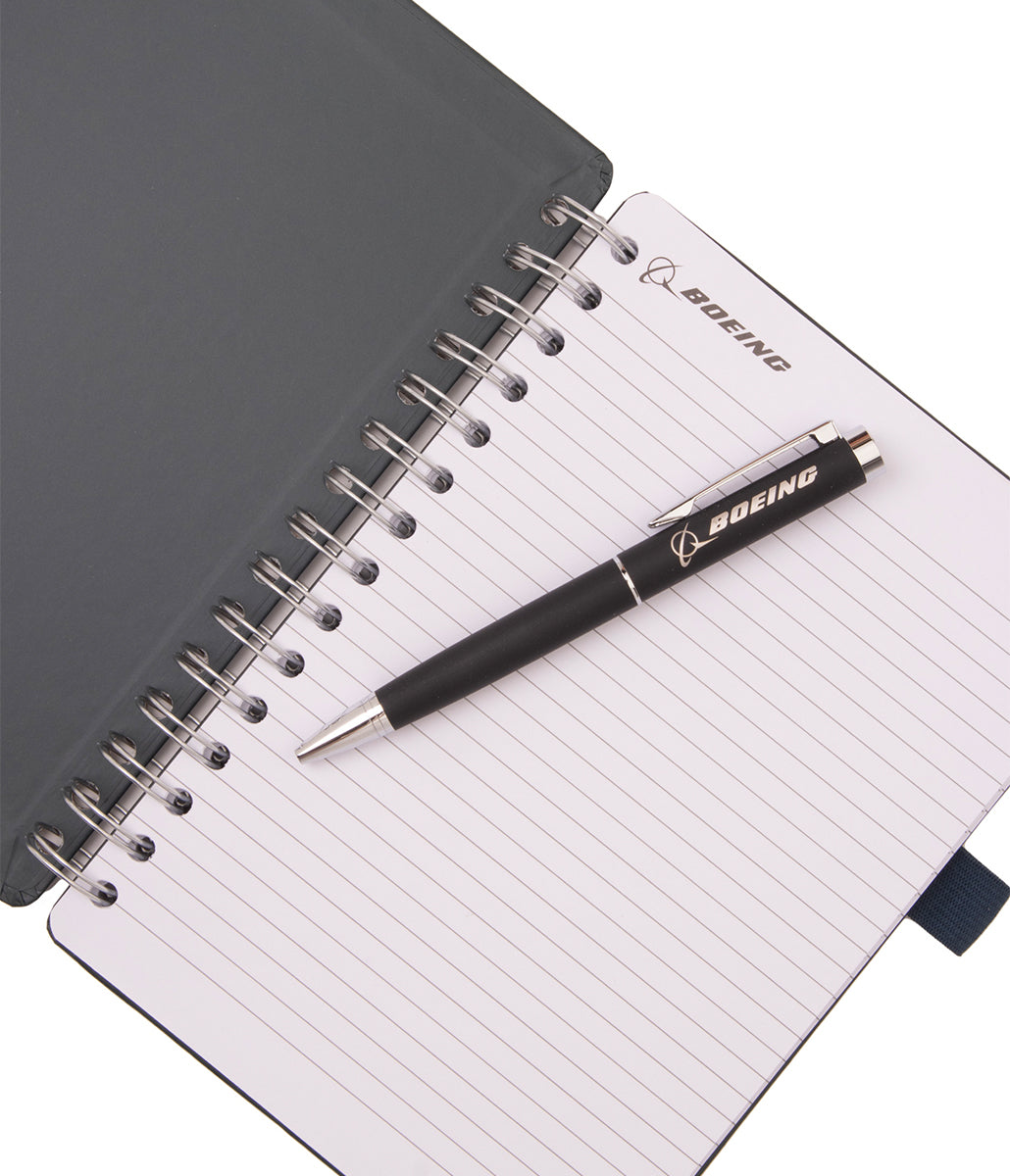 A Boeing AH-64 Apache Graphic Notebook Pen Set consisting of a spiral-bound notebook with lined pages and a black retractable pen resting on top.