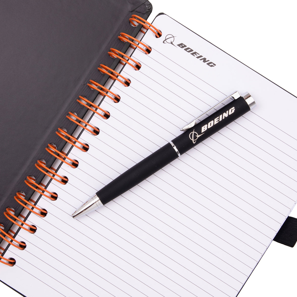 Boeing SLS Artemis II Graphic Notebook Pen Set featuring a spiral-bound lined notebook with an SLS Artemis II logo and a matching black ballpoint pen resting on the open leaf.