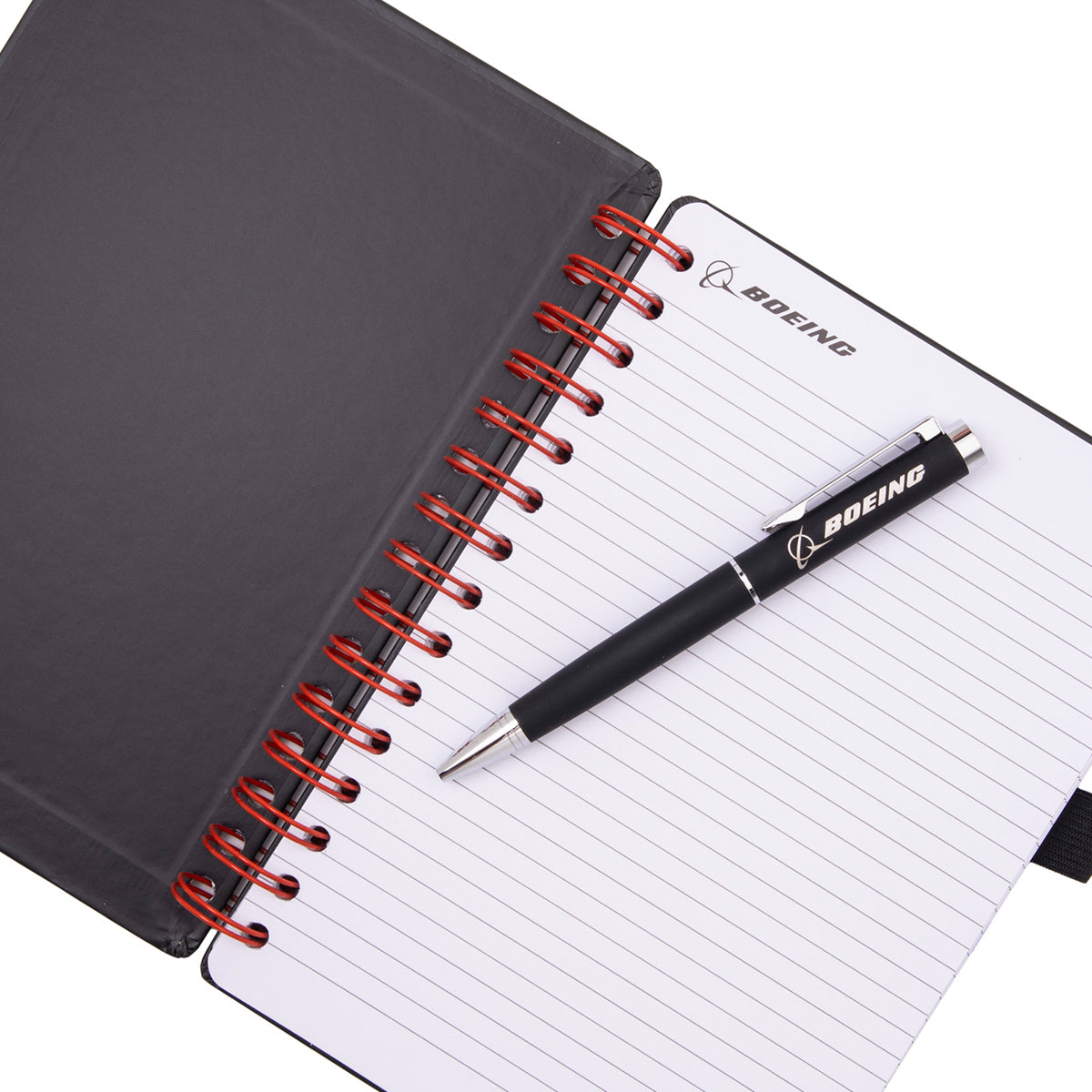 A black spiral-bound Boeing T-7A Red Hawk Graphic Notebook Pen Set with lined pages and a matching black ballpoint pen resting on top, both featuring a logo.