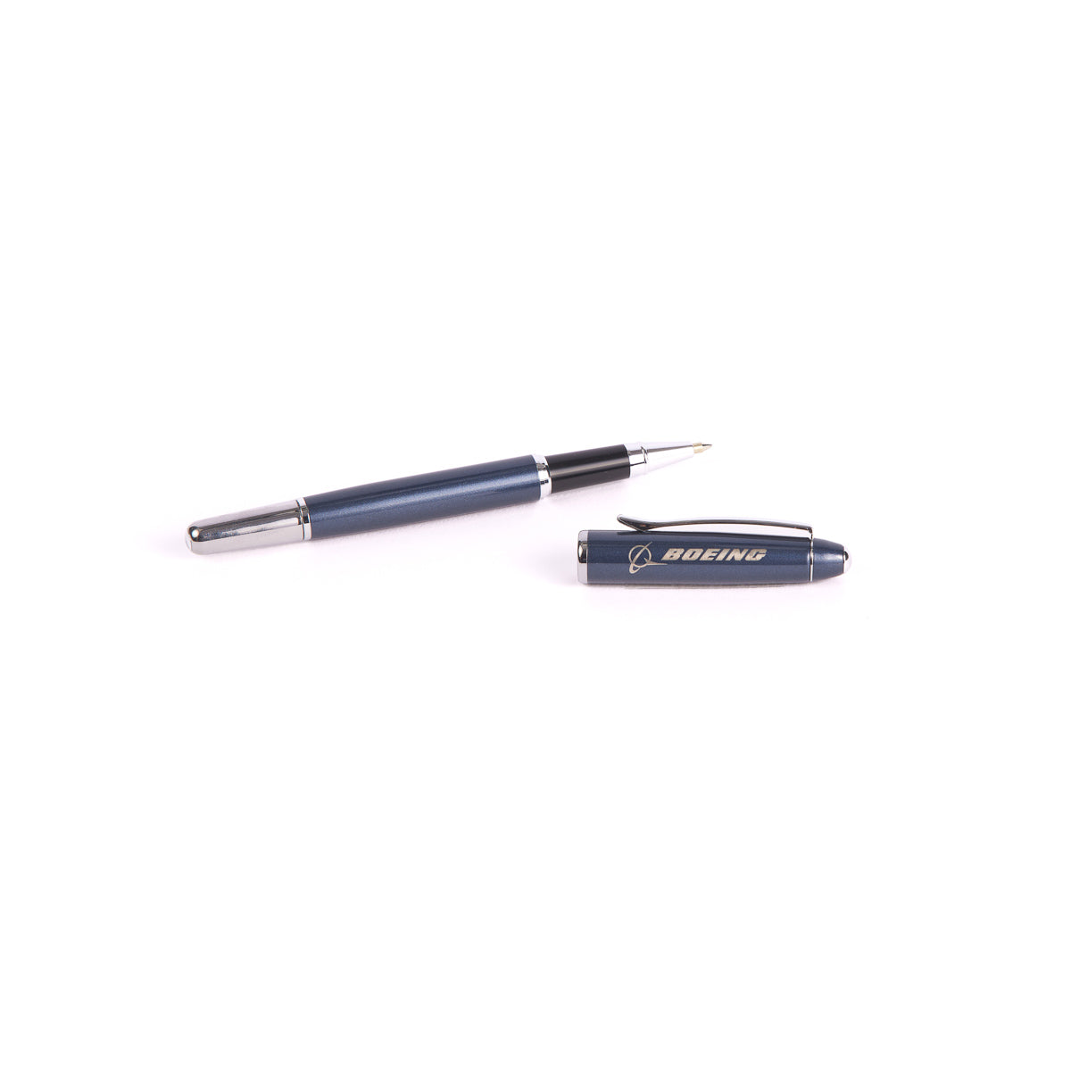 A blue and silver Boeing Shimmer Rollerball Pen from The Boeing Store is placed on the right side with its cap off. The cap features BOEING in gold, enhancing writing tasks with a smooth glide and stainless steel elegance.