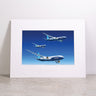 Framed and matted “Boeing 777X Family Matted Print - Large” by Boeing, featuring three blue Boeing airplanes soaring at varying heights against a clear blue background, with the Boeing logo embossed on the white mat.