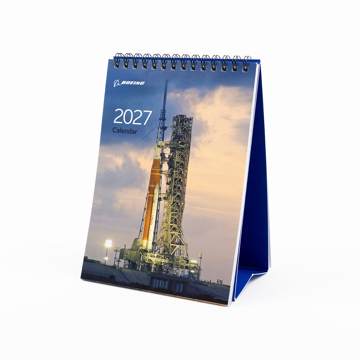 Introducing the Boeing 2027 Desktop Calendar by BOEING, featuring a stunning cover image of a rocket on a launchpad at dusk with the iconic Boeing logo displayed at the top. This calendar is perfect for aviation enthusiasts and fans of aerospace products.