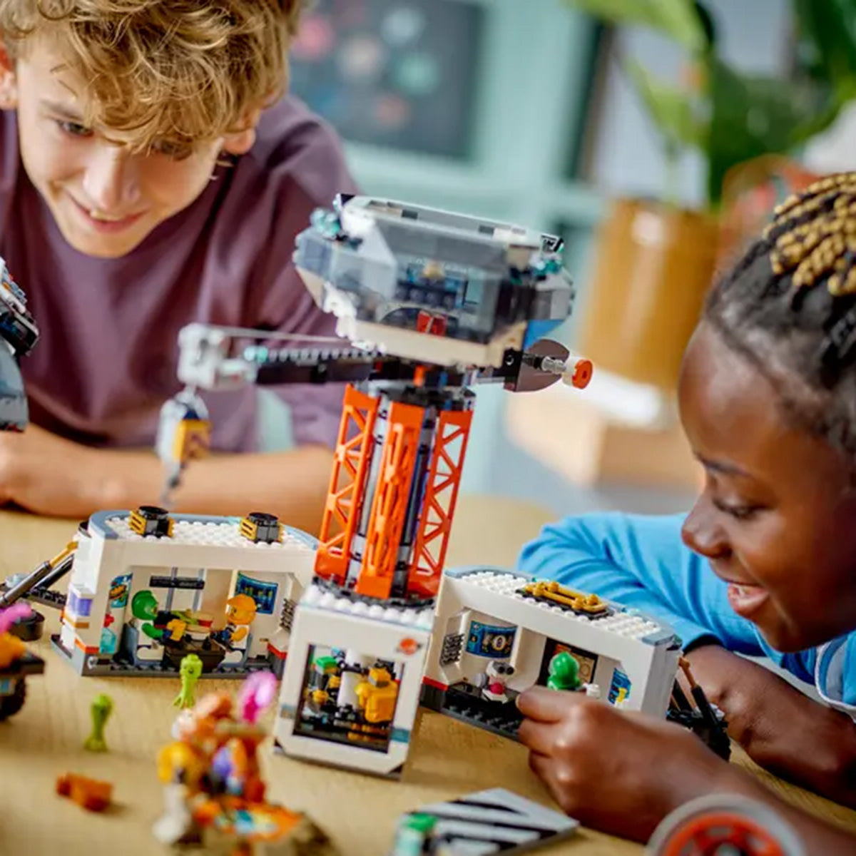 Two children smile and play with the LEGO® Space Base and Rocket set by LEGO, surrounded by mini figures and accessories. The colorful scene encourages imaginative role play and exciting space adventures.