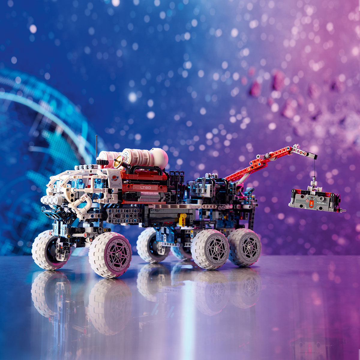The LEGO® Mars Crew Exploration Rover by LEGO features six wheels, a mechanical arm, and detailed equipment against a blue and pink space-themed backdrop—perfect for any space toy collection.