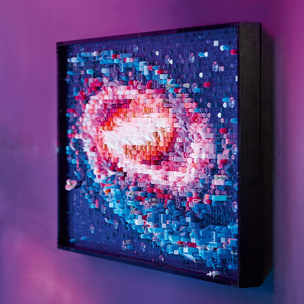 A colorful 3D mosaic of a spiral galaxy built from LEGO bricks, inspired by LEGO® The Milky Way Galaxy, is framed and displayed on a purple wall—a unique space-themed wall art and creative gift for any LEGO or astronomy fan.