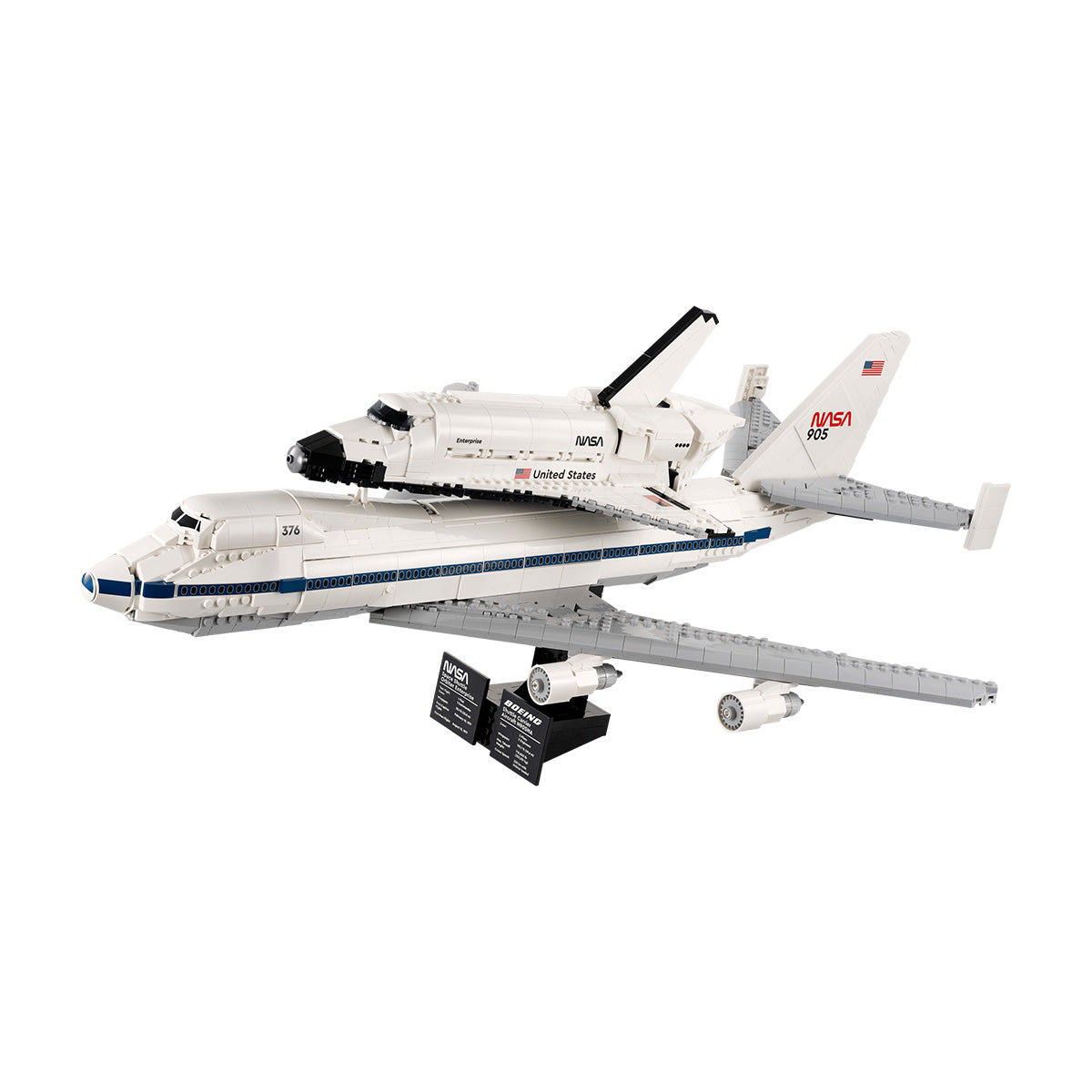 Here’s the sentence rewritten using your product data: The LEGO® Shuttle Carrier Aircraft by BOEING features a detailed Boeing 747 with blue stripes and twin engines, carrying the NASA Space Shuttle Enterprise—complete with authentic NASA markings—on its back. The display also includes informational plaques to highlight key details.