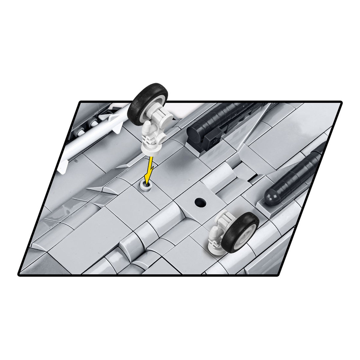 Close-up of a LEGO model car's underside, with a yellow arrow pointing to a circular detail between rear wheels—showcasing the same precision as found in BOEING’s COBI Boeing F-15EX Eagle II. The car mainly uses gray LEGO bricks.