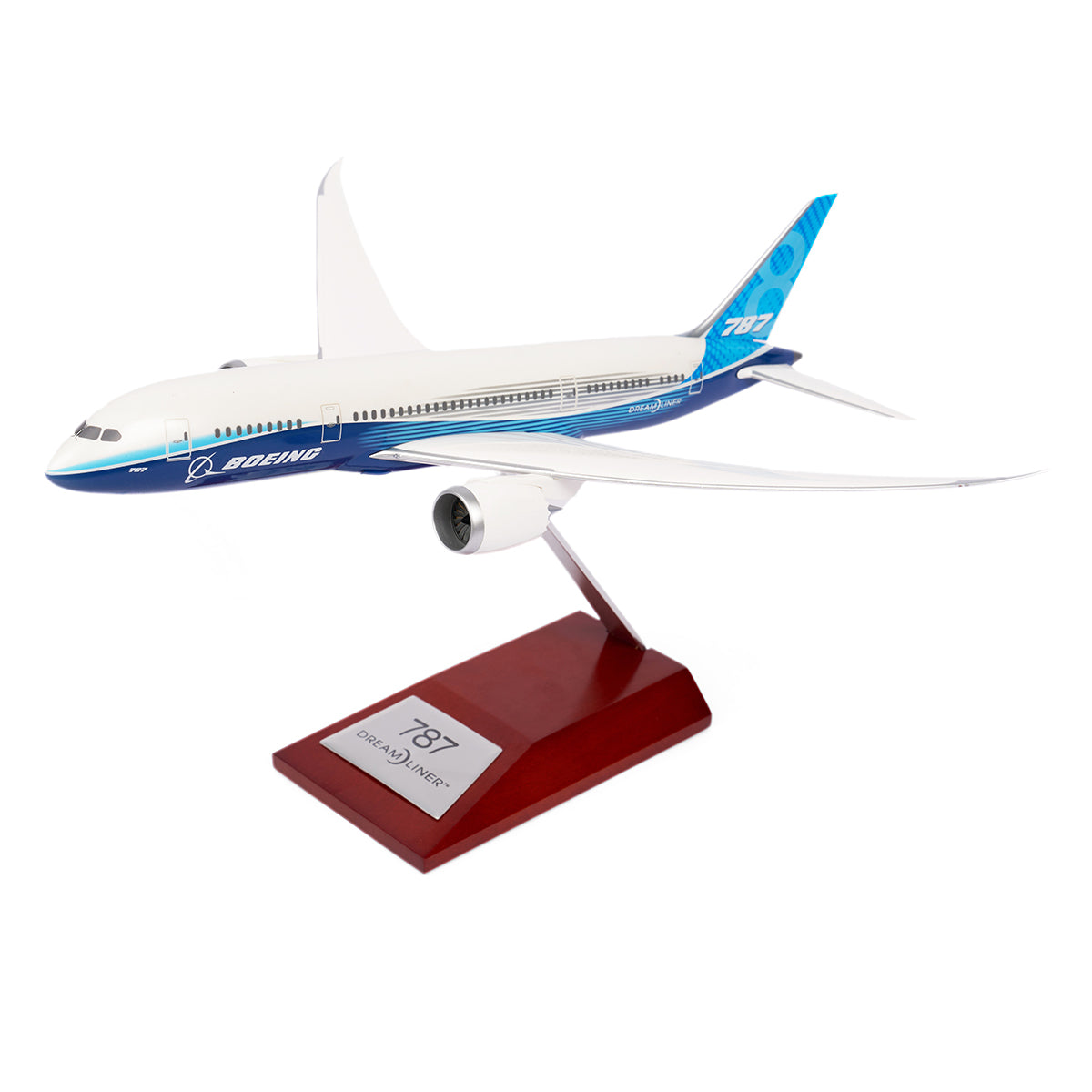 A sleek Boeing Unified 787-8 Dreamliner 1:200 model from The Boeing Store sits gracefully on a wooden stand, featuring a white body with blue accents. A plaque reads 787 Dreamliner, celebrating this marvel of modern aviation engineering.