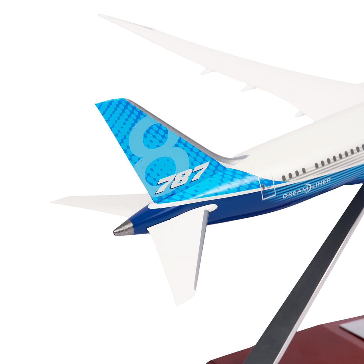 Close-up of a Boeing Unified 787-8 Dreamliner 1:200 Model from The Boeing Store shows the model airplanes tail with a blue and white design. The number 787 is on a blue checkered pattern, while Dreamliner is displayed on the fuselage, representing modern aviation excellence.