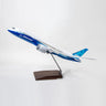 The PACMIN Boeing 787-8 Dreamliner Resin 1:100 Model features blue and white colors, is Boeing-approved, and comes mounted on a stand with a wooden base, set against a plain light background.