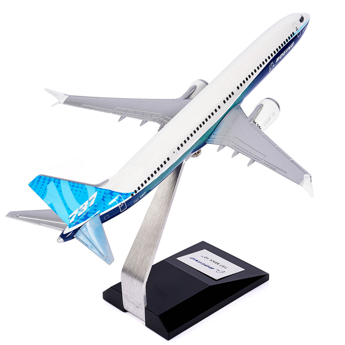 The Boeing Stores Boeing Unified 737 MAX 10 1:144 Model features blue accents and a unique blue tail, resting elegantly on a silver stand. Shot from a low angle against a white backdrop, it displays detailed wings with Advanced Technology winglets and engines. The stand includes a small plaque.